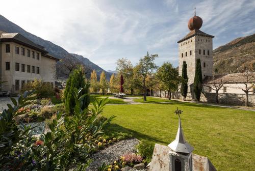 a church with a tower in the middle of a park at Gästehaus St. Ursula in Brig