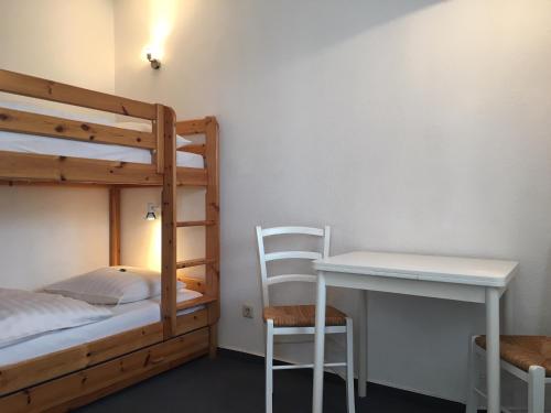a room with a bunk bed and a desk and a bed at Haus Bernstein Ferienwohnungen in Göhren