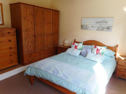 a bedroom with a bed and a wooden cabinet at Oak Lodge in Pembrokeshire