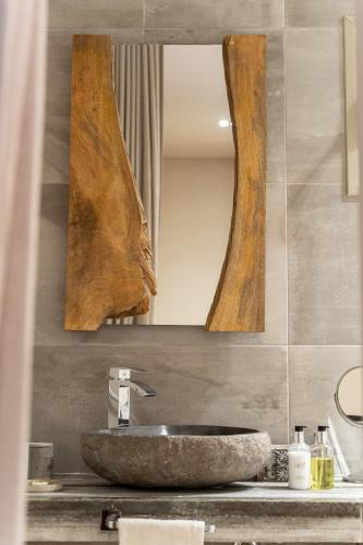 a bathroom with a stone sink and two mirrors at Mikelina Boutique Hotel in Pallíni
