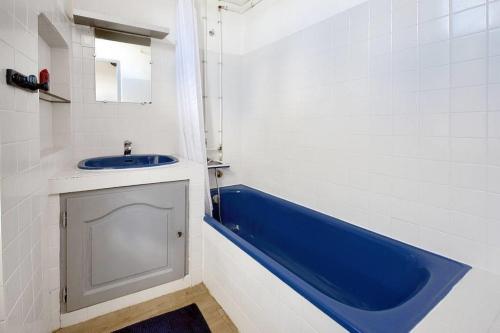 a bathroom with a blue tub and a sink at Appartement le Platane in Pertuis