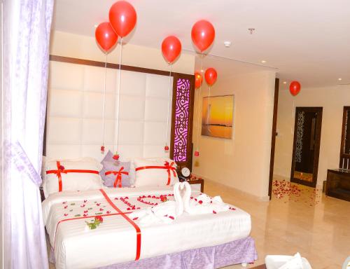 a bedroom with a bed with red balloons on it at Aster Hotel in Jeddah