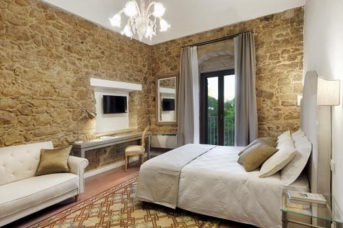 a bedroom with a king sized bed and a couch at Itria Palace in Ragusa