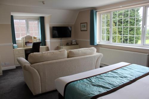 a living room with a couch and a desk and window at Badgers Mount Hotel in Earl Shilton