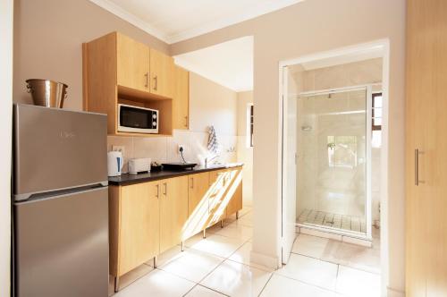 a kitchen with a stainless steel refrigerator and wooden cabinets at King Guest Lodge in Port Elizabeth
