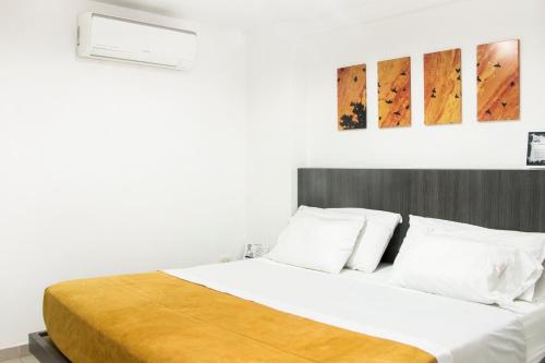 um quarto com uma cama grande com lençóis brancos e almofadas em Onix Hotel em Neiva