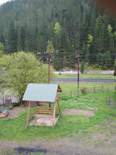 a wooden bench with a green roof in a field at Na Horbyku in Tatariv