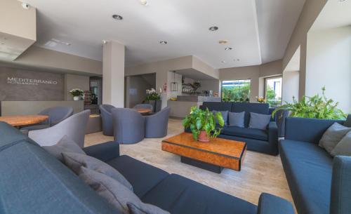 a living room with blue couches and a table at Mediterraneo Hotel & Suites in Cattolica