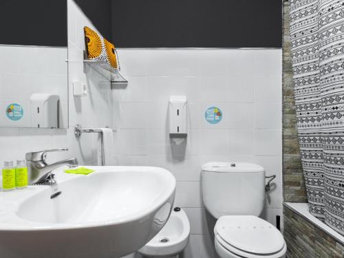 a white bathroom with a toilet and a sink at Hotel San Miguel in Gijón