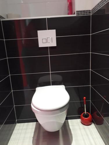a white toilet in a bathroom with black tiles at stephane et virginie in Villemandeur
