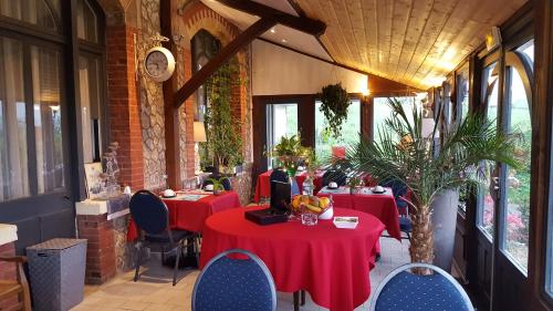 un restaurant avec des tables et des chaises rouges et une horloge dans l'établissement Les Cloches de Corneville, à Corneville-sur-Risle