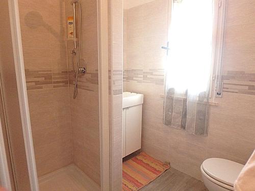 ein Bad mit einer Dusche und einem WC in der Unterkunft Pagoda 15 - Appartamento fronte mare con servizio spiaggia in Lido di Pomposa