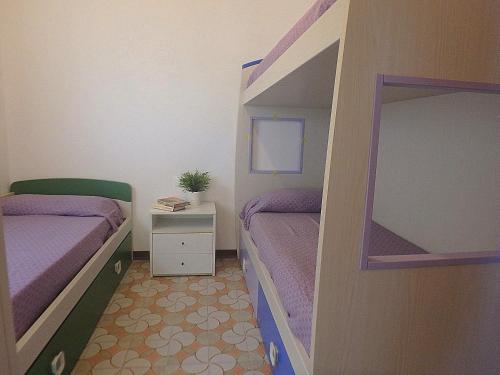 ein kleines Schlafzimmer mit 2 Etagenbetten mit lila Bettwäsche in der Unterkunft Pagoda 15 - Appartamento fronte mare con servizio spiaggia in Lido di Pomposa