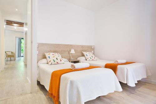 a bedroom with two beds with white sheets and orange blankets at BcnStop Parc Güell in Barcelona
