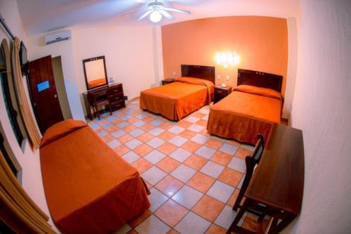 Habitación de hotel con 2 camas y espejo en Hotel Los Girasoles, en Tepic