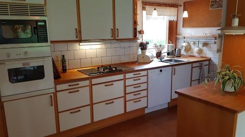 a kitchen with white cabinets and white appliances at Sænehus Husmandssted in Allinge