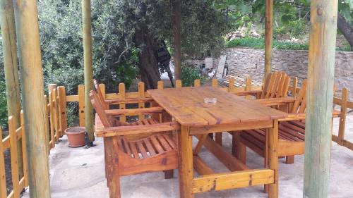 una mesa de madera y sillas sentadas bajo un cenador en Studios Ntina, en Alyki