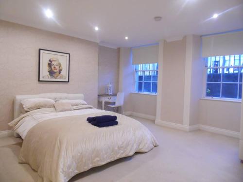 a white bedroom with a large bed and two windows at WEST END -Stunning, 2 bedroom, main door flat with private parking in Glasgow