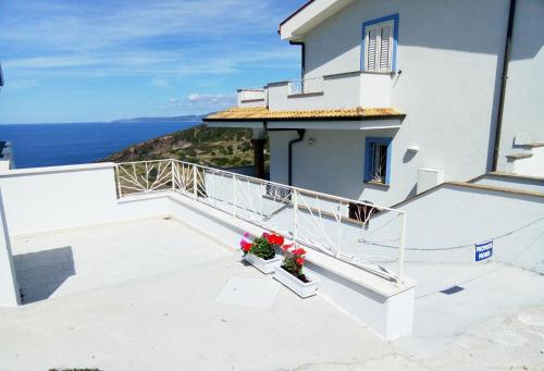 a white house with a balcony with flowers at Appartamenti Rocca 'Ja in Castelsardo
