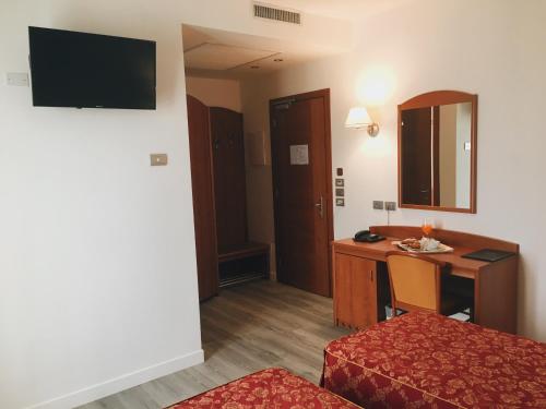 a hotel room with a desk and a bed and a table at Hotel Alla Croce in Negrisia