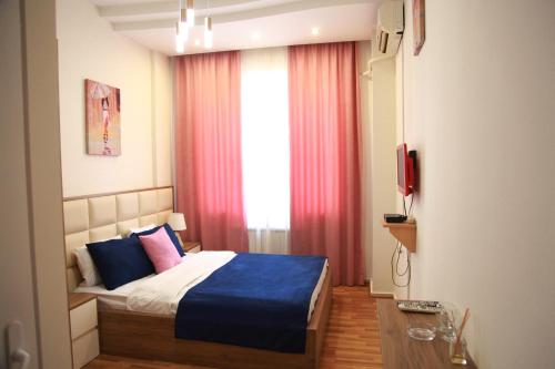 a bedroom with a bed with blue and pink pillows at Rio in Tbilisi City