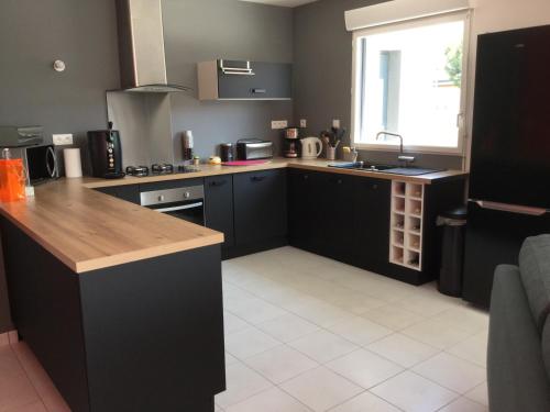 d'une cuisine avec des placards noirs, un évier et une fenêtre. dans l'établissement maison individuelle 500 m de la mer, à Agon-Coutainville