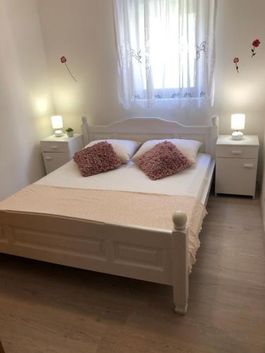 1 dormitorio con 1 cama con 2 almohadas y ventana en Apartments Vrdoljak, en Pag