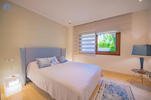 sypialnia z białym łóżkiem i oknem w obiekcie Luxury apartment at Lomas del Rey, Puente Romano w Marbelli