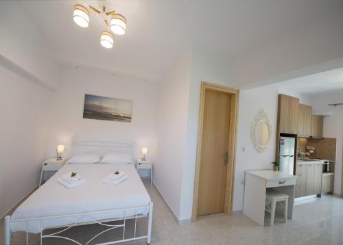 a white bedroom with a bed and a kitchen at Bounatsa Studios & Apartments in Nydri