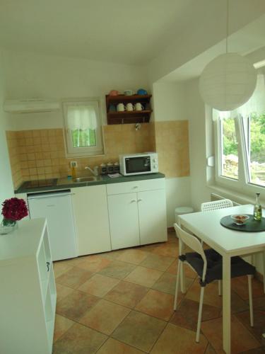 a kitchen with white cabinets and a table and a microwave at COSTABELLA VISTA in Rijeka