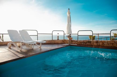 a swimming pool with two chairs and an umbrella at Beach of Eden Cefalu' in Cefalù