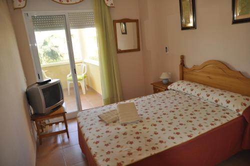 Un dormitorio pequeño con una cama y un televisor. en Estrella Blanca II, 2 dormitorios, by Bookindenia, en Denia