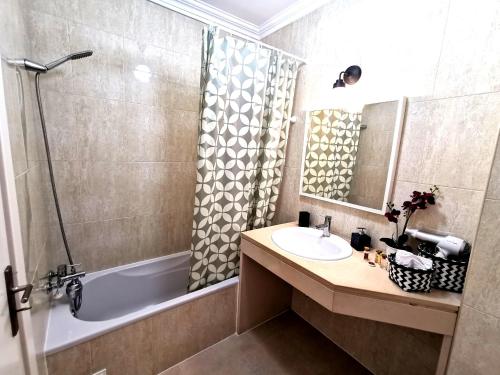 uma casa de banho com um lavatório, uma banheira e um chuveiro em Apartamento Jeni Residencia Flamingo em Portimão