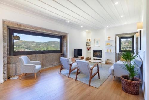 a living room with a table and chairs and a large window at Mariana's HeartMade House in Caldelas