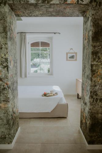 a white bedroom with a bed and a window at Ca Muretta Relais in Bardolino