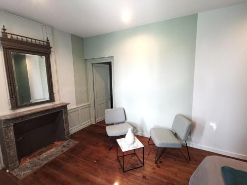 a living room with two chairs and a fireplace at Manoir des Carreaux Chambres d'hôtes in Ingouville