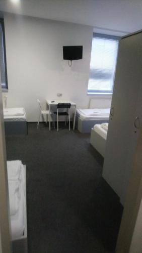 a room with two beds and a table and a tv at Hotel & Hostel Letov in Prague