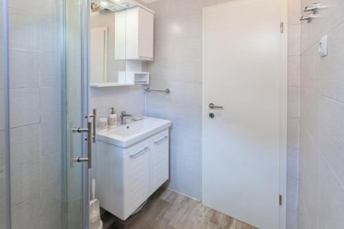 a white bathroom with a sink and a shower at Apartment Ema in Premantura