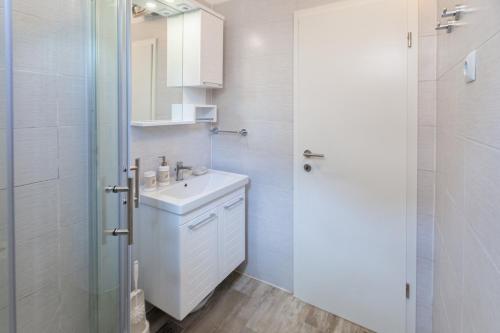 a white bathroom with a sink and a shower at Apartment Ema in Premantura