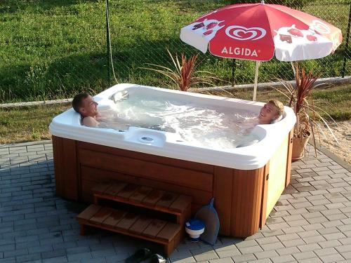 two people in a hot tub under an umbrella at Penzion U Fábů in Lednice