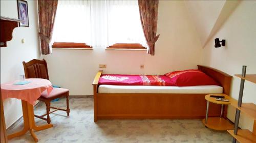 a small bedroom with a small table and a bed at Pension Wiesengrund in Seebach