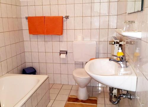 a bathroom with a toilet and a sink and a tub at Pension Wiesengrund in Seebach