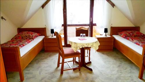 a room with two beds and a table and a table and chairs at Pension Wiesengrund in Seebach