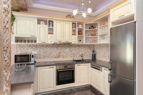 cocina con armarios blancos y nevera de acero inoxidable en Mountain Resort Residences, en Ždiar