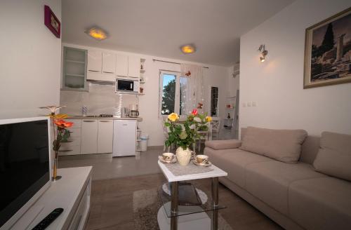 a living room with a couch and a table with flowers at Apartman Karla in Solin