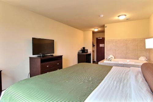 a bedroom with a bed with a television and a tub at AmeriVu inn and Suites - Crookston in Crookston