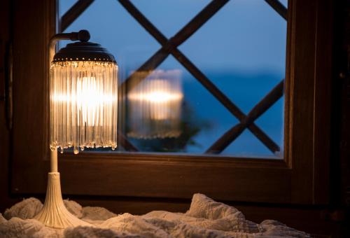 a lamp sitting on a table next to a window at Paradosiako Saratsi - Traditional Guest House in Volos