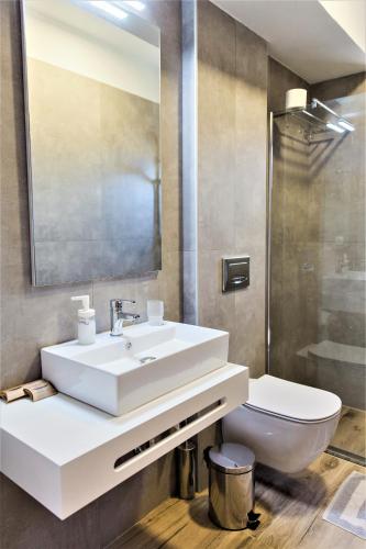 a bathroom with a white sink and a toilet at Aggelos Apartments & Deluxe Studios in Nydri