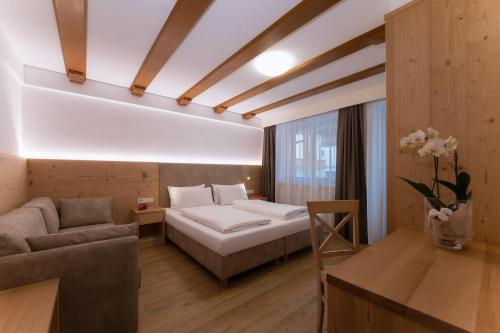 Habitación de hotel con cama y sofá en Villa Caterina en Corvara in Badia