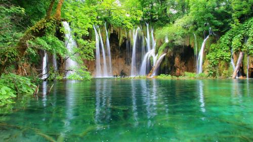 a waterfall in the middle of a pool of water at House Pox in Plitvička Jezera